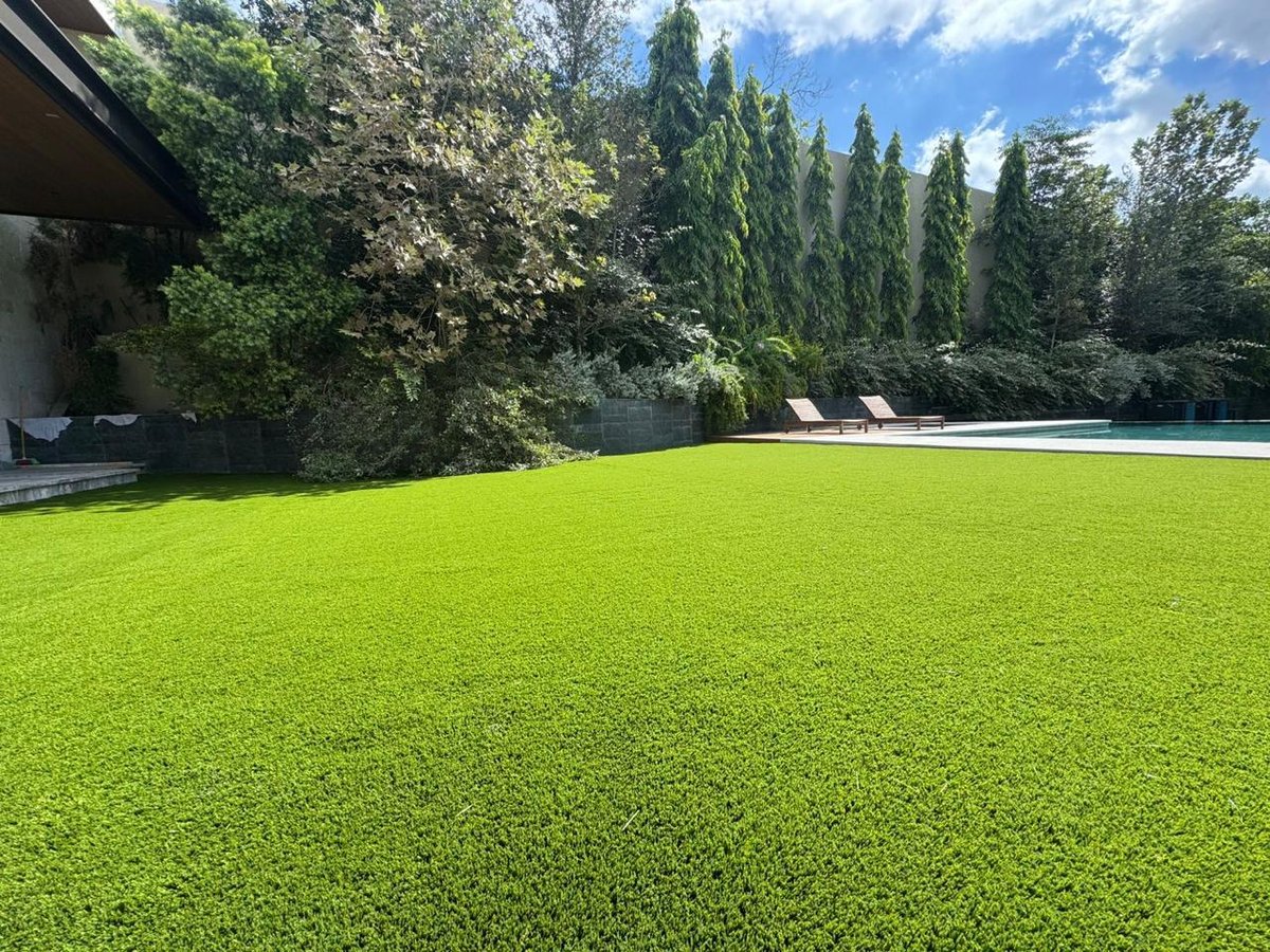 Jardín residencial premium con pasto sintético EasyGarden — alberca, camastros y vegetación natural
